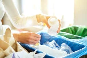 Woman-Putting-Empty-Plastic-Bottle-In-Recycling-Bin-In-The